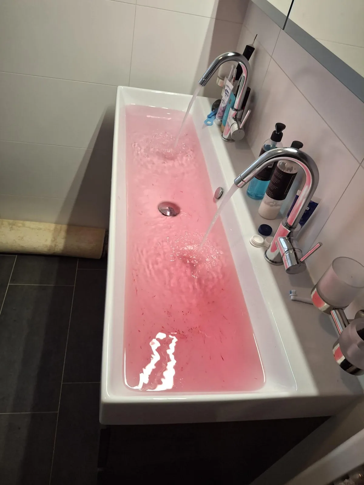 Dubbele wastafel met roze gekleurd water