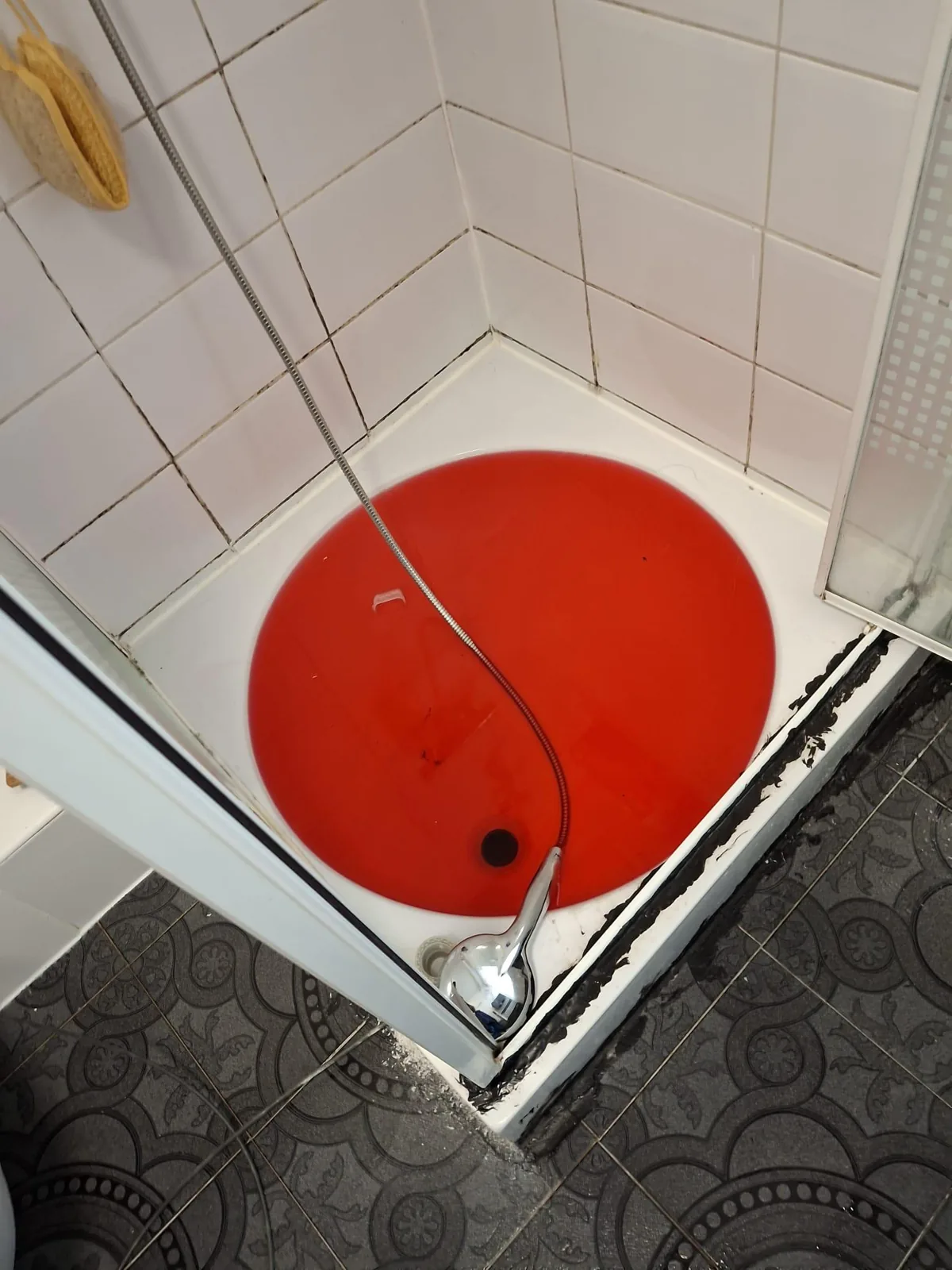 Douchebak met rood gekleurd water