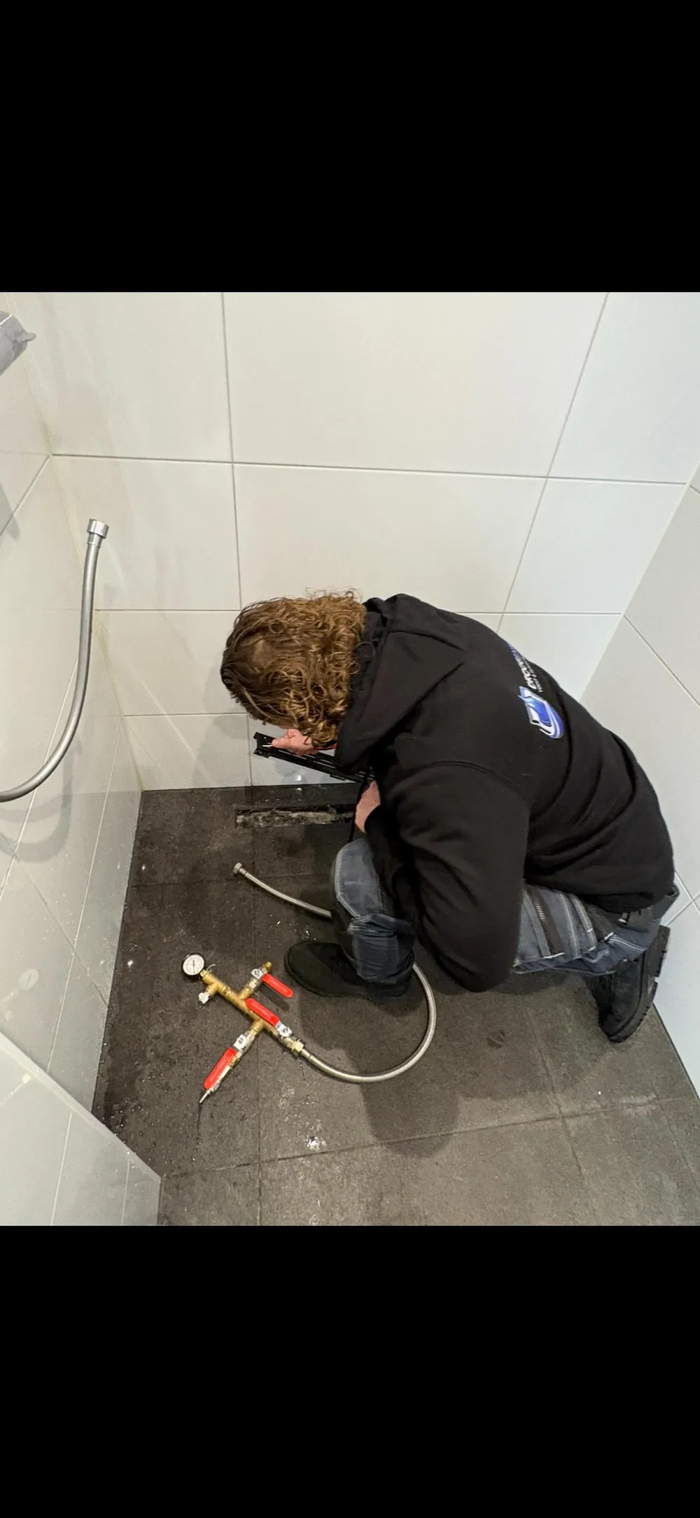 Medewerker bij een douchegoot met meetgereedschap