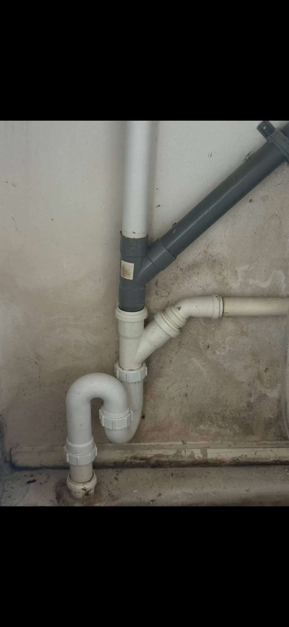 Zichtbare afvoerleidingen langs een wand